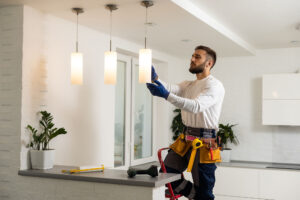 Electrician installs lamp lighting and spot loft style on ceiling